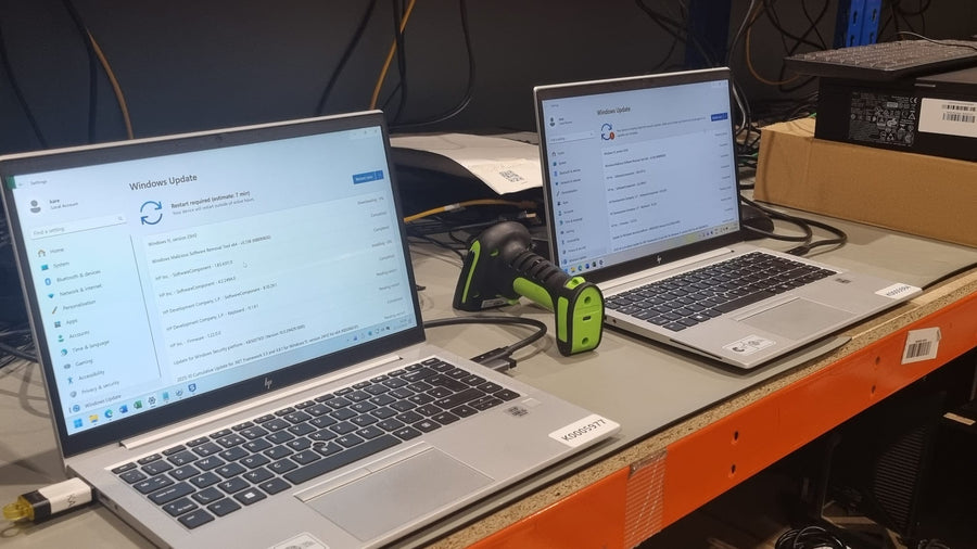 Refurbished HP laptops updating beside a barcode scanner
