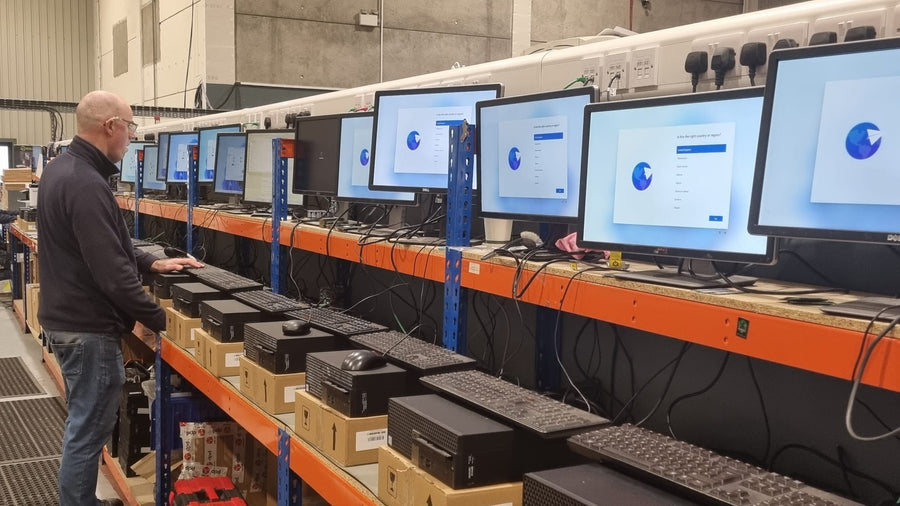 A GreenIT technician setting up refurbished desktops on Windows 11